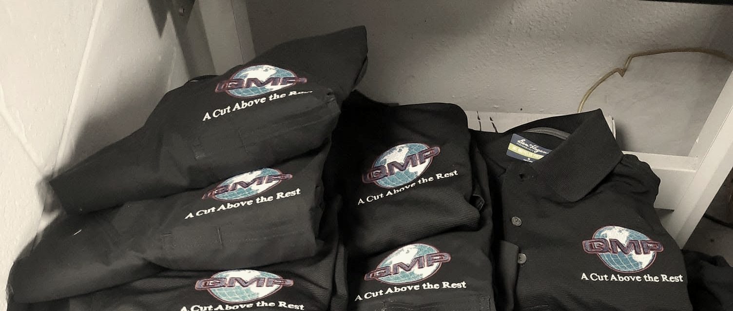 Stacks of folded black polos with an embroidered globe logo on the chest