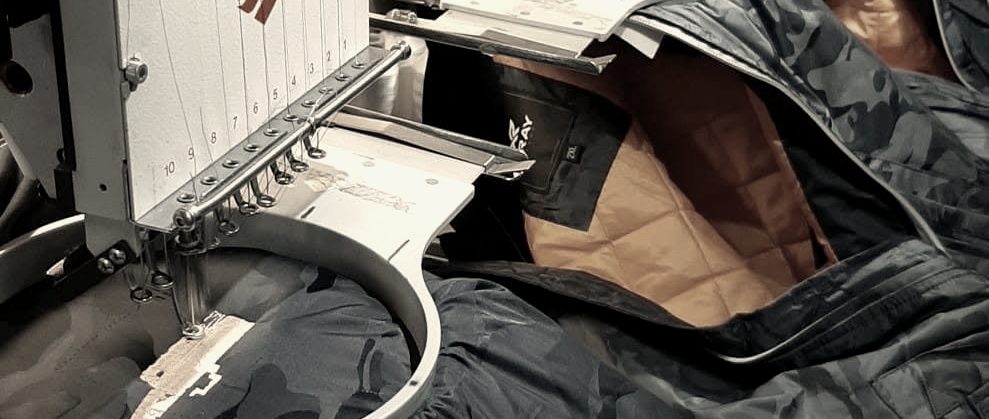 Navy jackets with orange lining hooped across a multi-head embroidery machine at MMM Embroidery