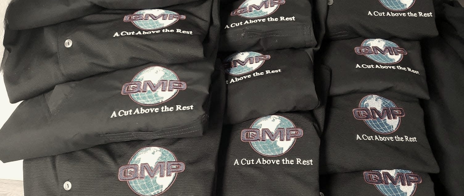 Two stacks of black polos with an embroidered globe logo on the chest, folded and ready for pickup