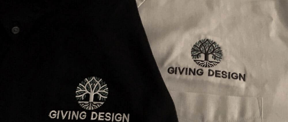 A black polo and a white polo with the same tree logo embroidered on the chest