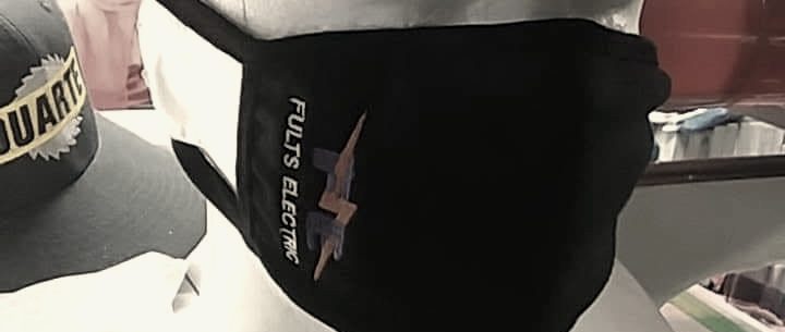 A black face mask embroidered with an electrical contractor's logo, on a mannequin head under an olive cap