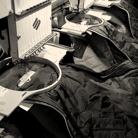 Navy jackets with orange lining hooped across a multi-head machine