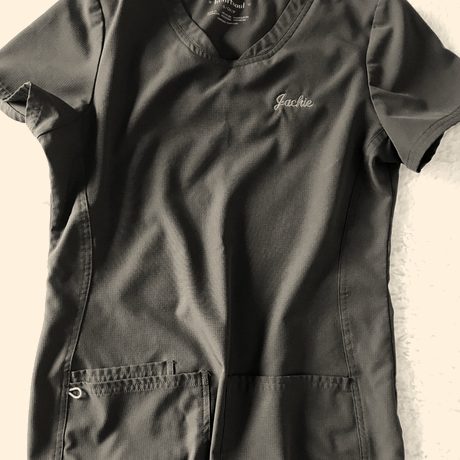 A charcoal scrub top with a first name embroidered in pink script