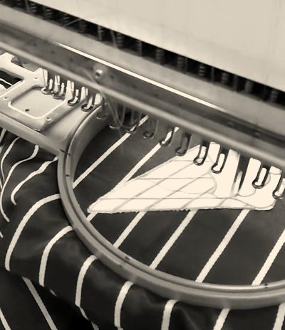 A pinstripe apron hooped under a Barudan embroidery head