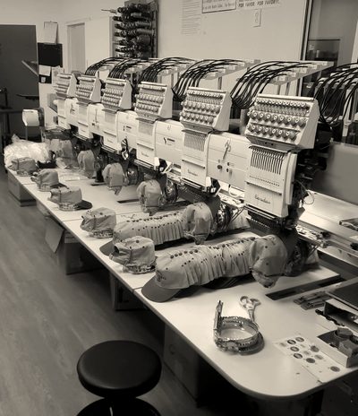 A row of Barudan embroidery heads with caps on the cap frames
