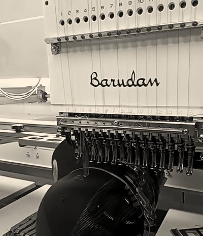 A Barudan embroidery head over a black cap on a cap frame