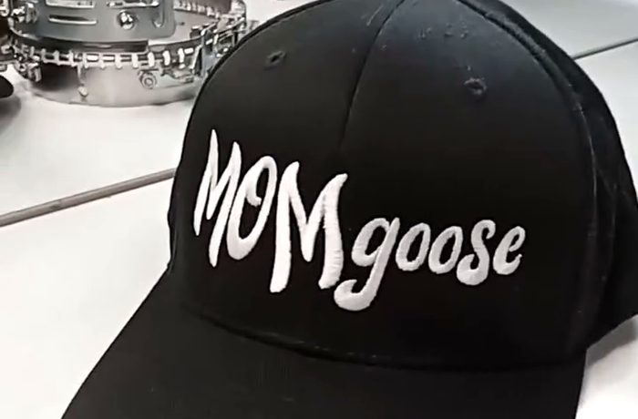 A black cap with a word embroidered in white script across the front