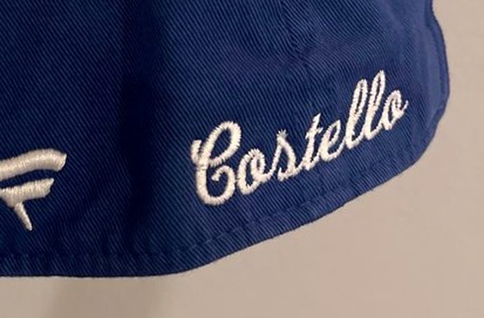 A name embroidered in white script on the side of a navy cap