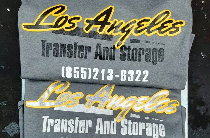 A stack of grey t-shirts with a company name printed across the front