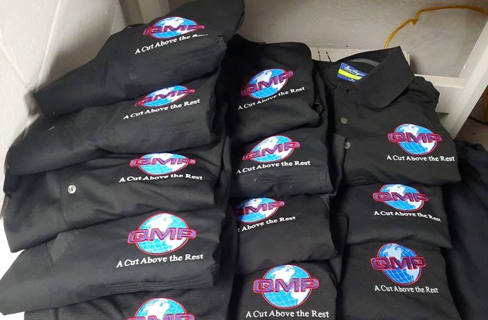 A stack of black polos with an embroidered logo on the left chest