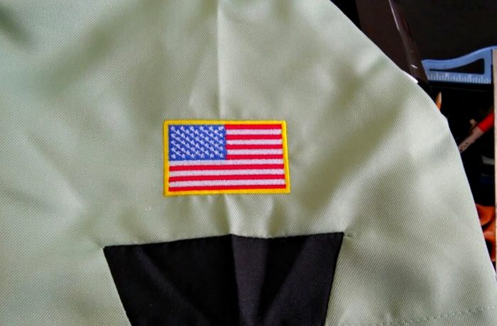An embroidered US flag on the sleeve of a sage uniform shirt