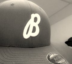 A maroon cap with an embroidered script letter on the front