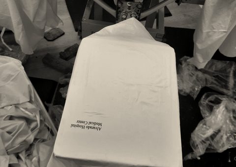 A yellow nylon garment on the platen of a screen-printing press