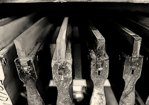 Screens with dried ink in several colors, standing in a rack