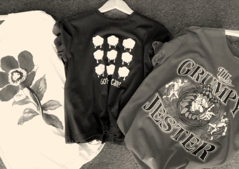 Three printed t-shirts on hangers: a flower, small icons and a jester