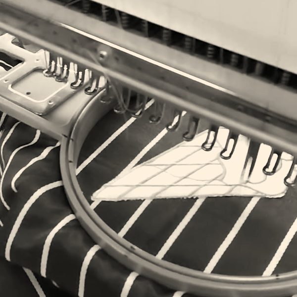 A black and white pinstripe apron hooped under a Barudan head