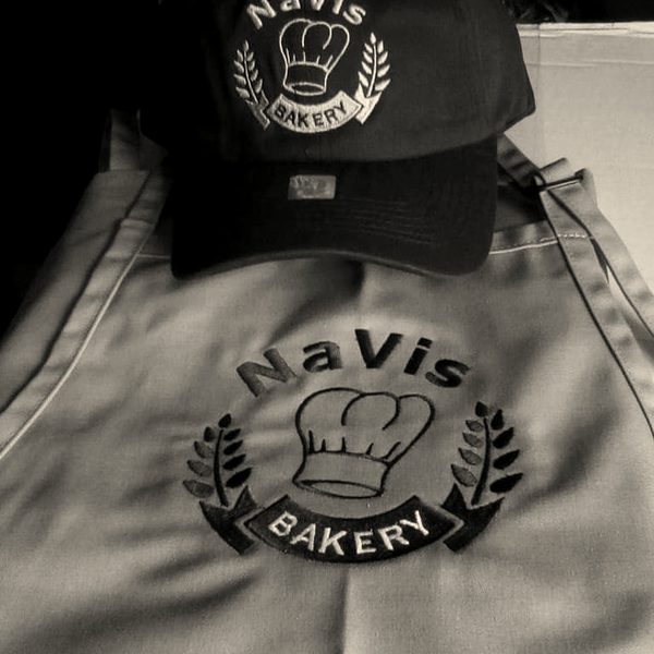 A brown cap and a grey apron, both embroidered with a bakery's chef-hat logo