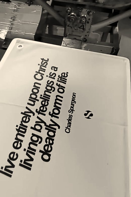 A cream canvas banner printed with black lettering on the platen of an orange carousel press