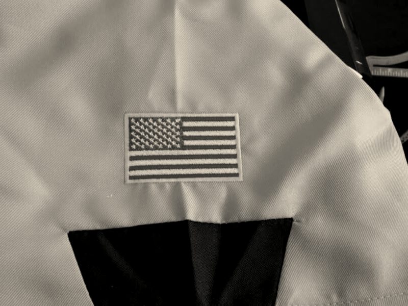 An embroidered US flag on the sleeve of a sage uniform shirt
