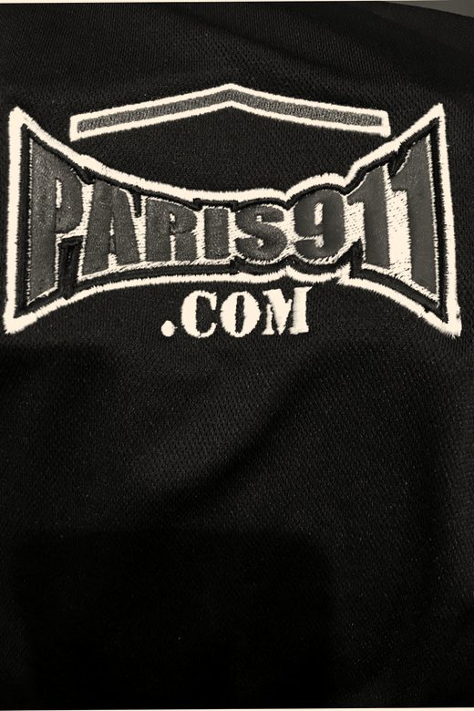 A close-up of a blue, red and white logo embroidered on a black polo