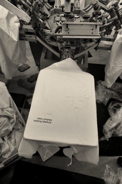 A yellow nylon piece on the platen of an orange carousel screen printing press