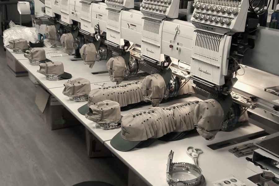 A row of Barudan multi-head machines with caps on the cap frames