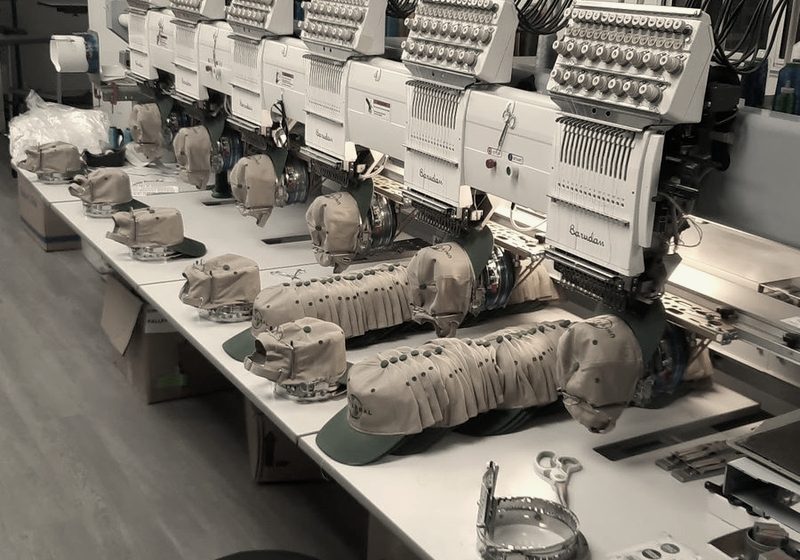 A row of Barudan multi-head machines with caps on the cap frames