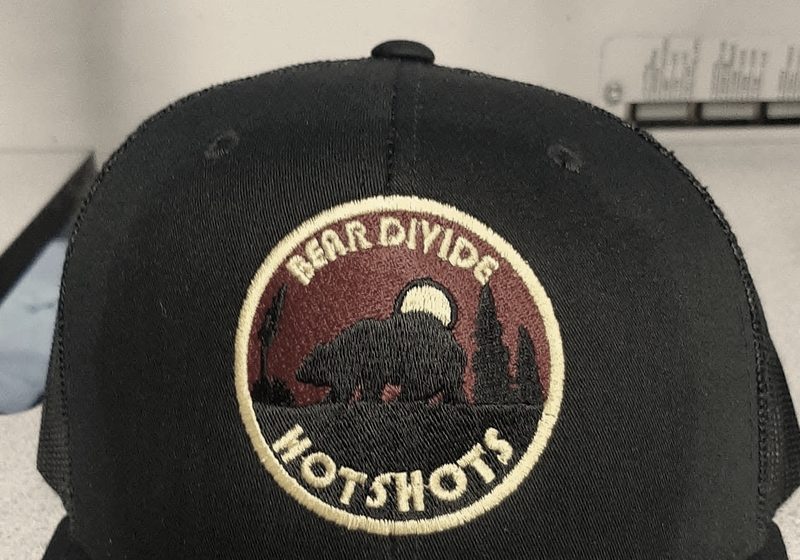 A finished black trucker cap with a round embroidered patch