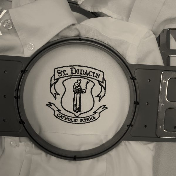 A school crest stitched in maroon on a white shirt, still in the blue hoop