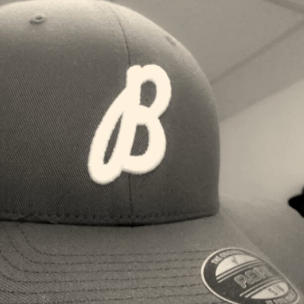A maroon fitted cap with a white script letter on the front