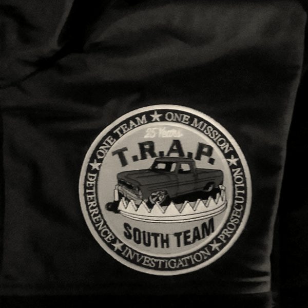 A round embroidered team patch with a blue pickup truck on a navy jacket