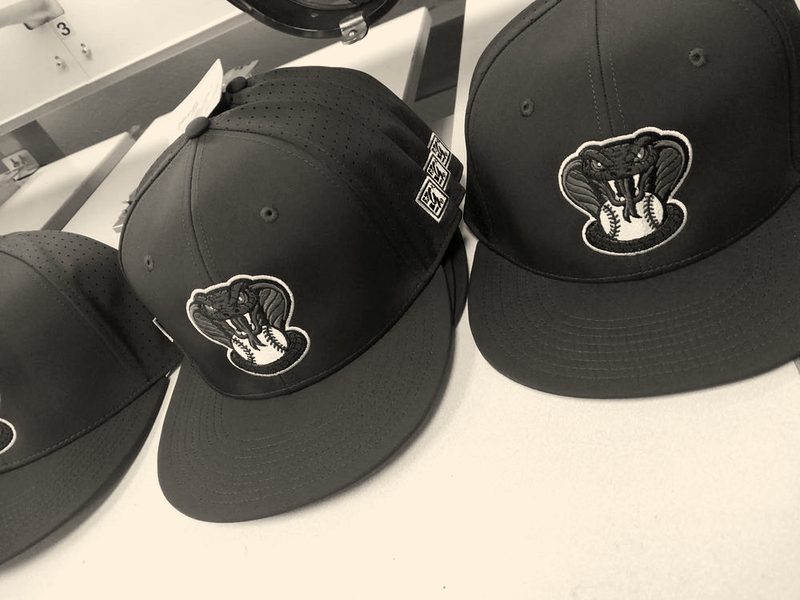 Navy fitted caps with a green snake-and-baseball team logo
